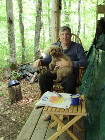 This is me and attack dog Millie, on the camp’s front porch, breakfast dishes done, with the New York Times and a cup of coffee, enjoying the sound of—nothing.